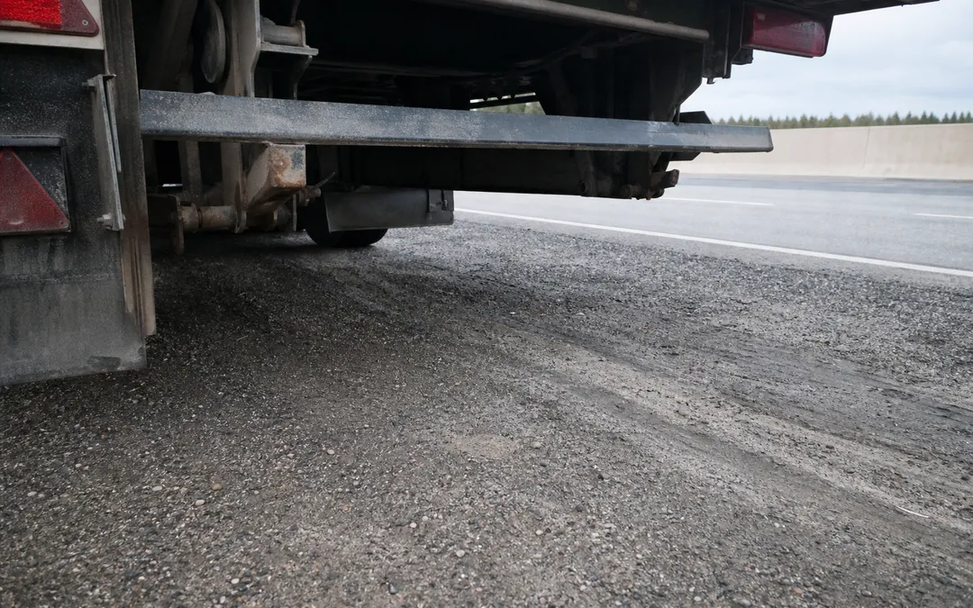 Undersidan av ett lastbilssläp med underkörningsskydd synligt, fotograferat på motorväg