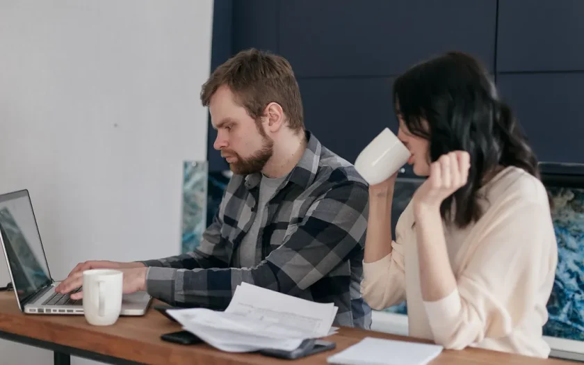 Två kaffekoppar och en anteckningsbok vid ett köksbord där ett par driver företag tillsammans